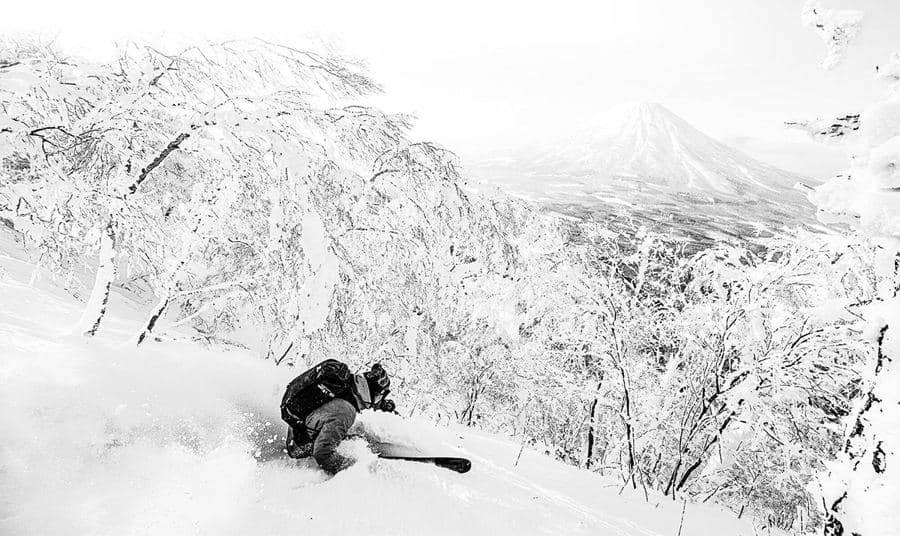 日本の雪に覆われた森でパウダーを滑るスキーヤー